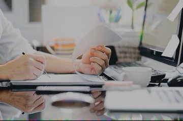 cropped-shot-man-hand-using-pencil-writing-clipboard-while-sitting-office-desk-working-with-computer_44344-1284